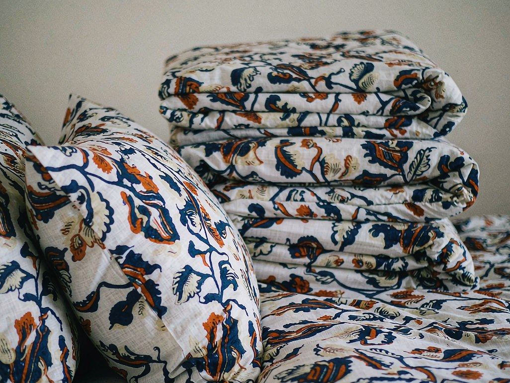 Printed polyester cushions and folded bedding in a botanical pattern