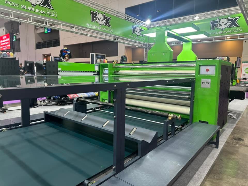 A wide-format roller heat transfer machine carrying printed textile, with FOX branding on the machine