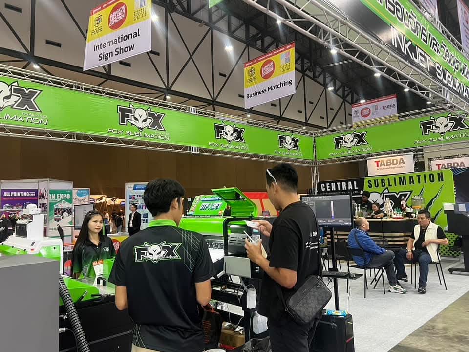 People meeting at an exhibition stand with printing equipment on display