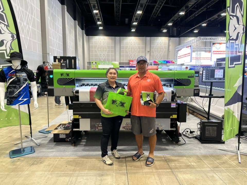 Two people standing beside a large-format printing machine at a digital printing exhibition