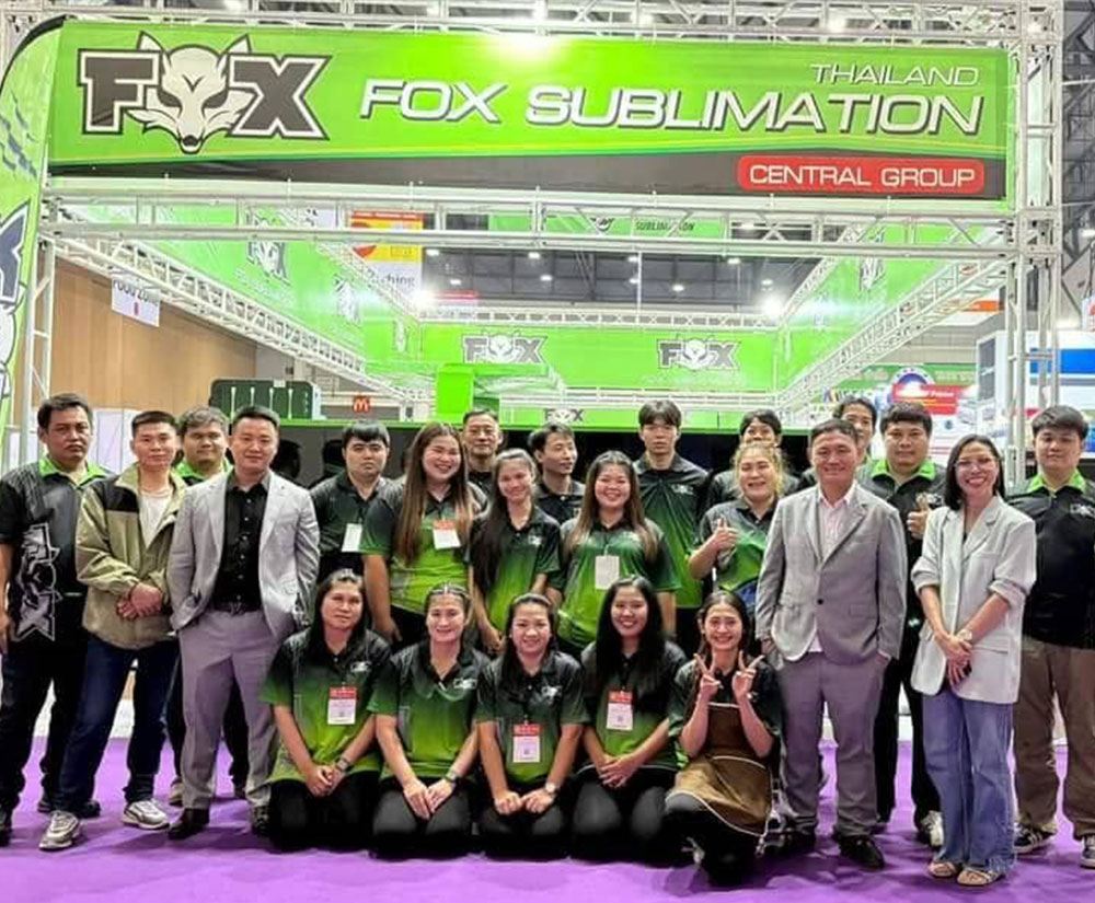 Three FOX Thailand team members in FOX-branded uniforms standing in front of a container filled with cartons and roll materials
