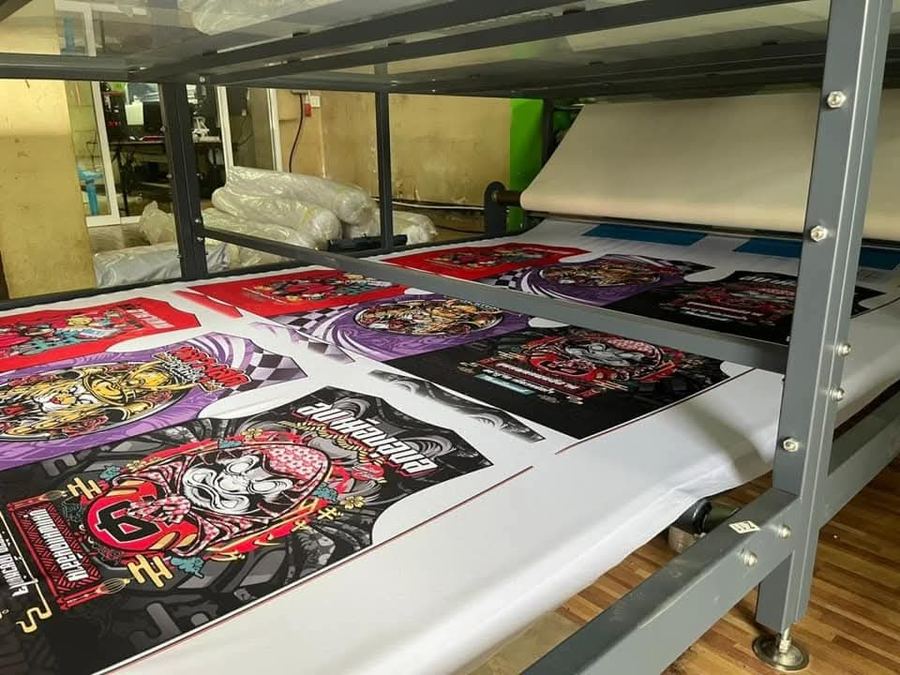 Printed DTF transfer sheets resting on a production rack after the powder and curing stage