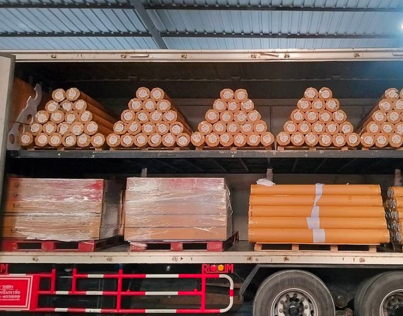 Wrapped roll pallet being craned into a shipping container for export